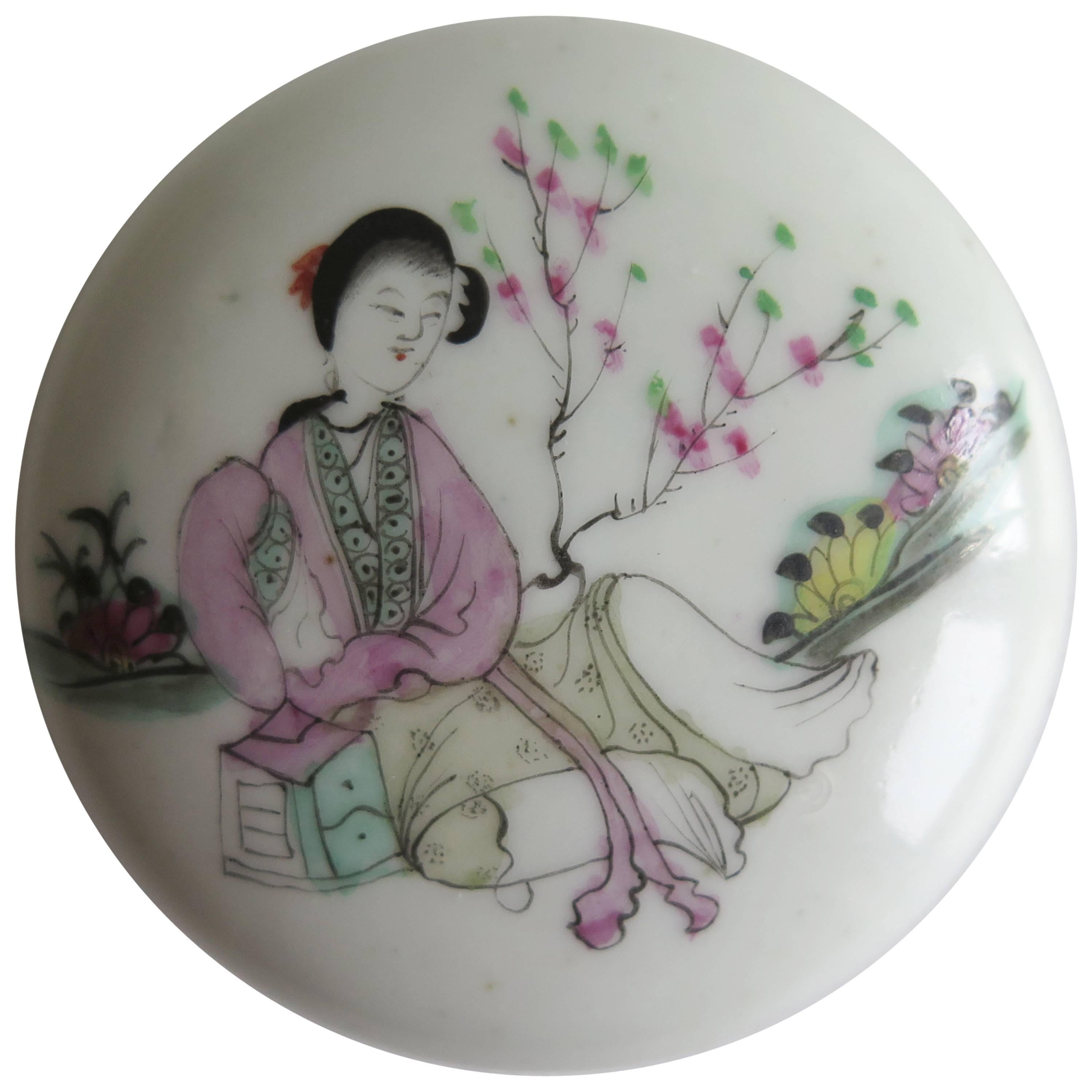 This is a very decorative, circular porcelain Box with Lid, made in China, circa 1900 to 1910 

The box is hand painted in the Famille Rose palette, the lid decorated with a lady sat beside a cherry tree in a garden setting, with flowers either