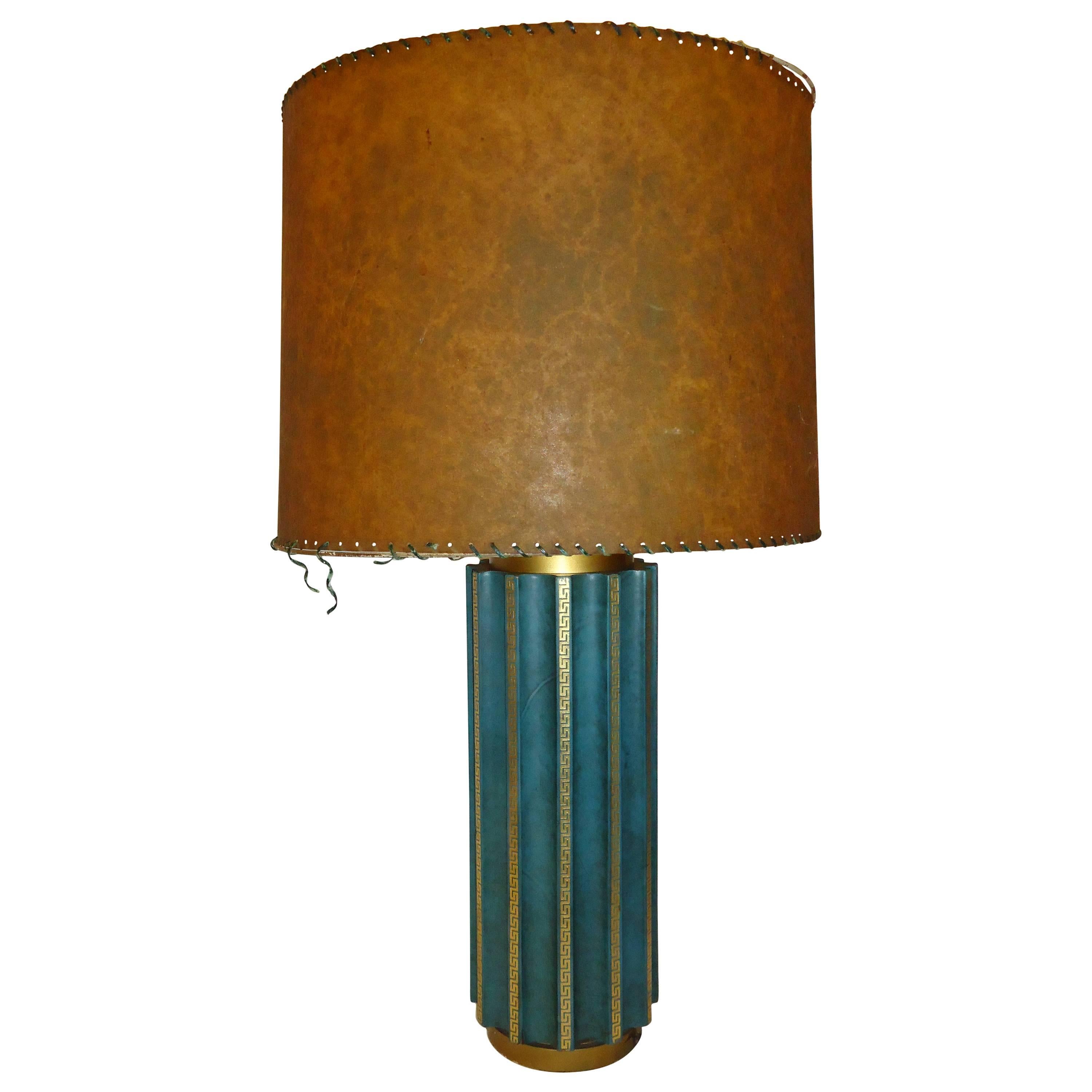 Unusual neoclassic fluted teal green leather cased table lamp in the style of Tommi Parzinger. 
Beautiful green dyed lambskin or goatskin leather covered lamp body that is  fluted with striking vertical lines of embossed gilt Greek key decoration on