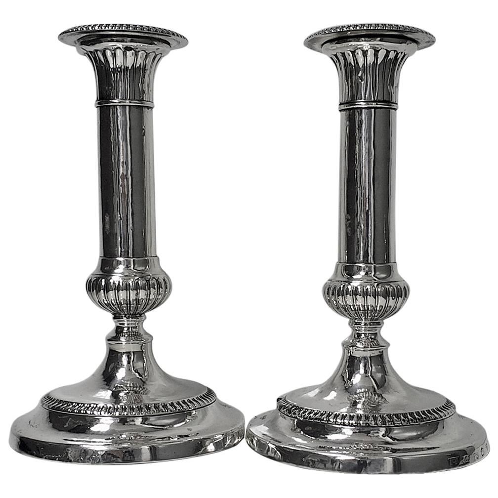 Antique Georgian sterling silver candlesticks, hallmarked for 1805, John Roberts & Co., of Sheffield. The candlesticks with removable gadroon nozzles on domed gadroon bases, rising to plain cylindrical stems with fluted knops. The bases with crests