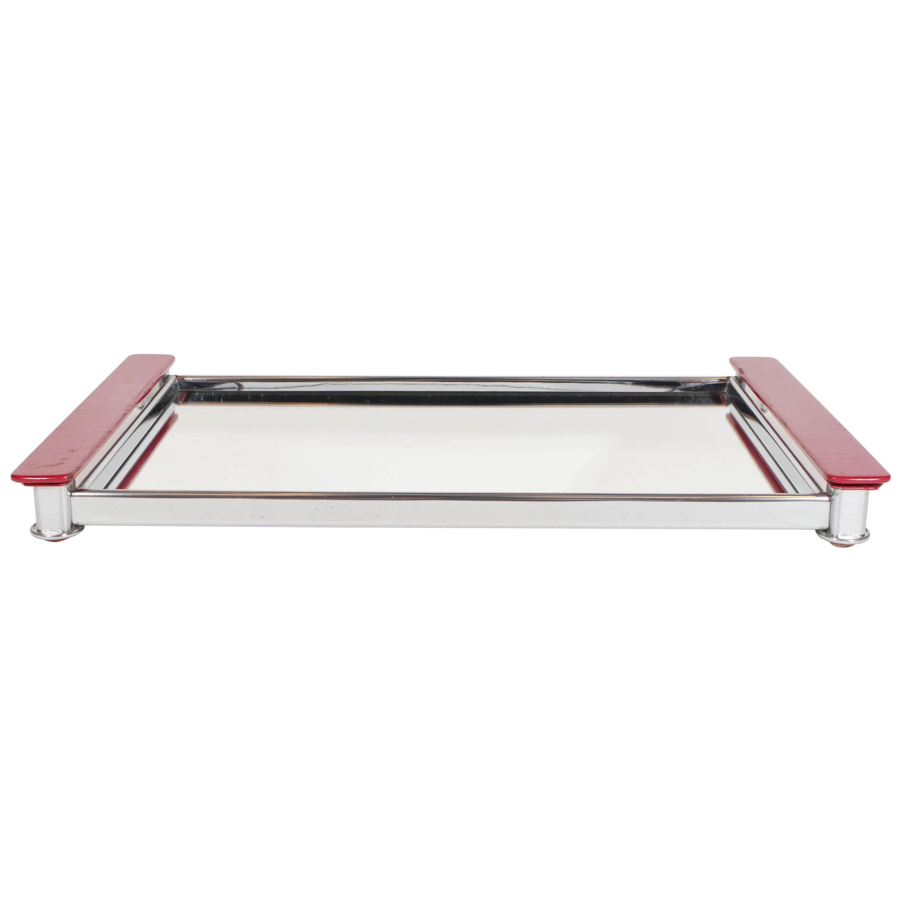 Art Deco serving tray with Machine Age design. The tray has a streamlined polished chrome frame and features a mirrored center with wonderful lacquered wood handles in a vibrant red. Excellent addition to any barware collection or as a vanity tray