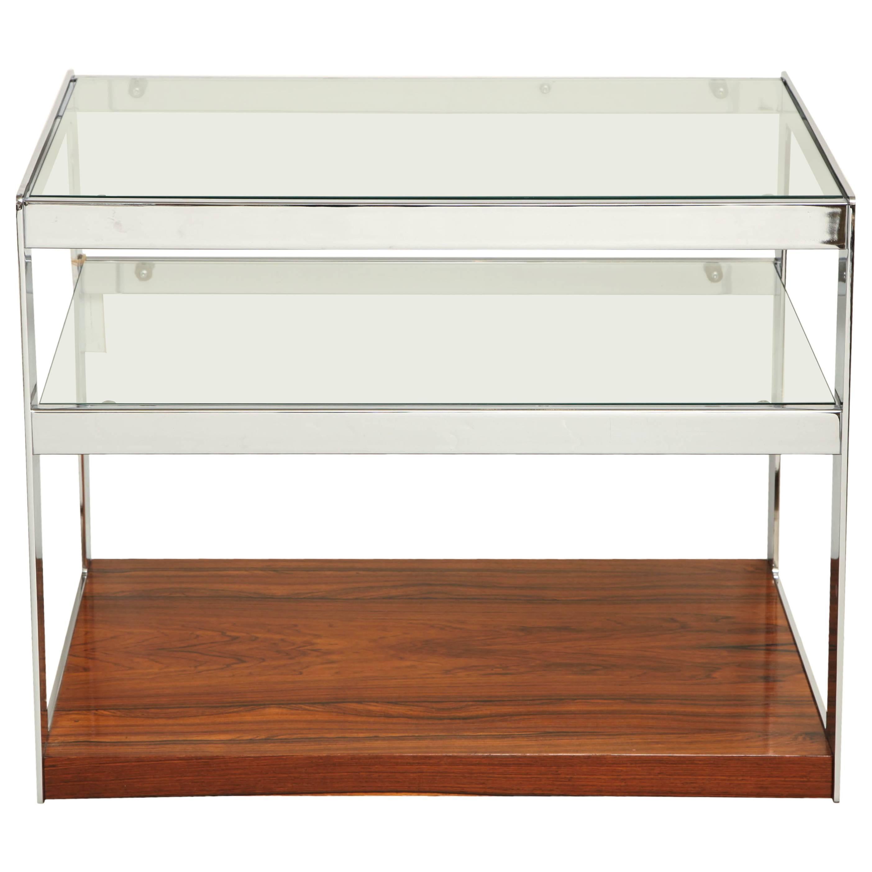 Two-tiered chrome bar cart with glass shelves and rosewood base on hidden castors. Designed by Richard Young for Merrow Associates, UK. Two available.