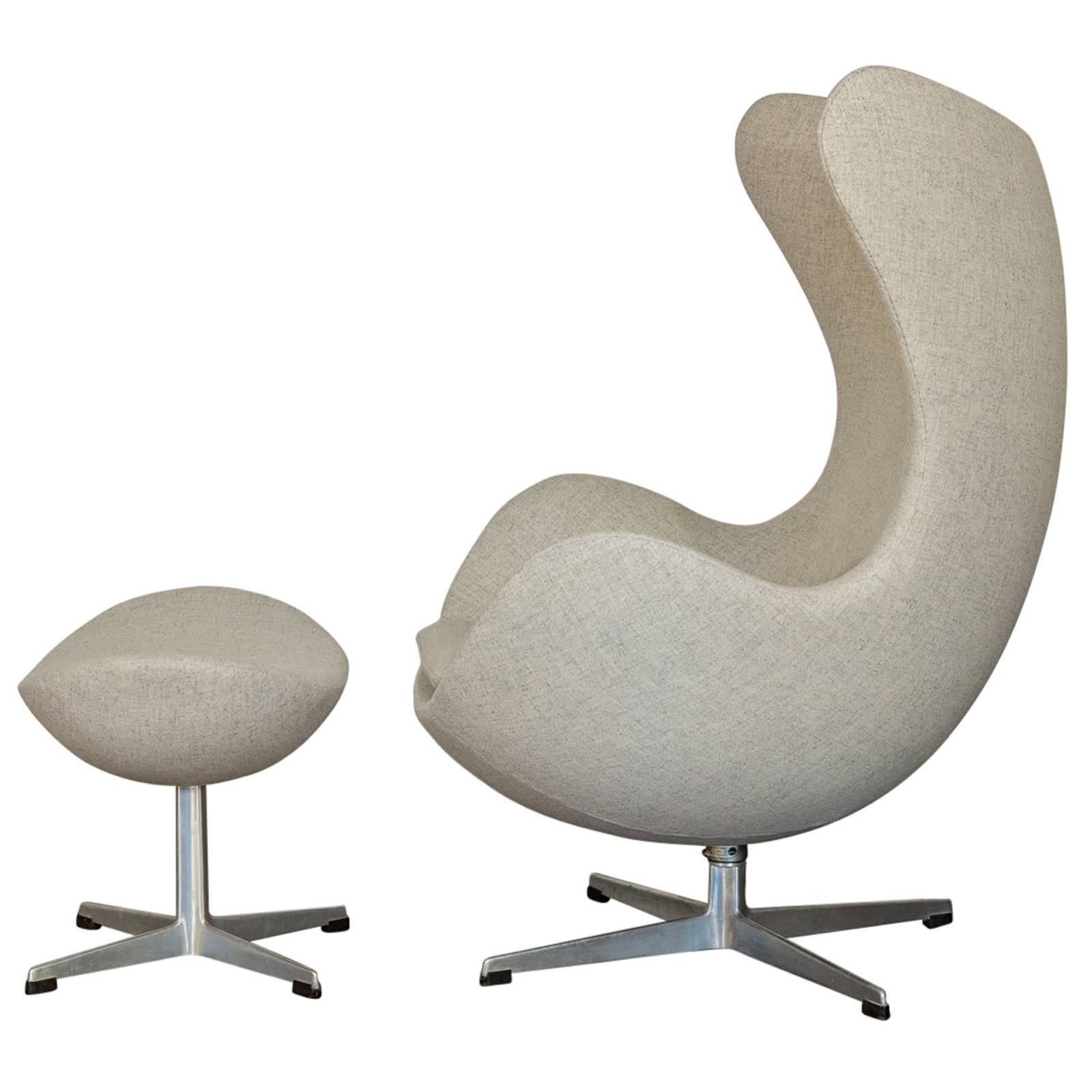 The iconic Egg chair and matching footstool designed by Arne Jacobsen in 1958. Our chair dates to the 1960s and has been meticulously upholstered in pale gray Tonica wool. Superbly comfortable. Swiveling four-star base. Made by Fritz Hansen and