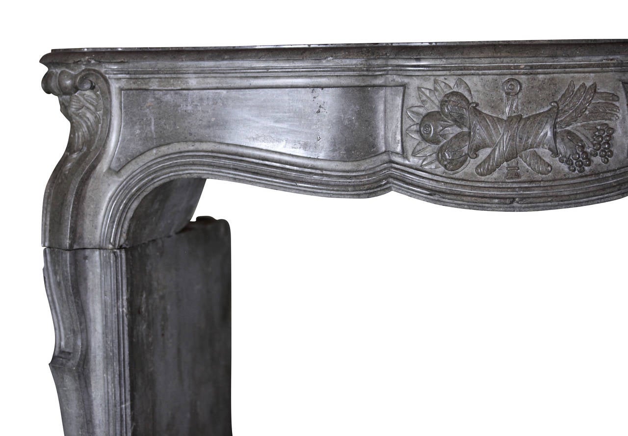 This is an exceptional Louis XIV transition Regency period antique fireplace surround. It has a central cartouche carved with horns of abundance. If you slide your hand across the stone, the sensation brings out the art and craftsmanship of its