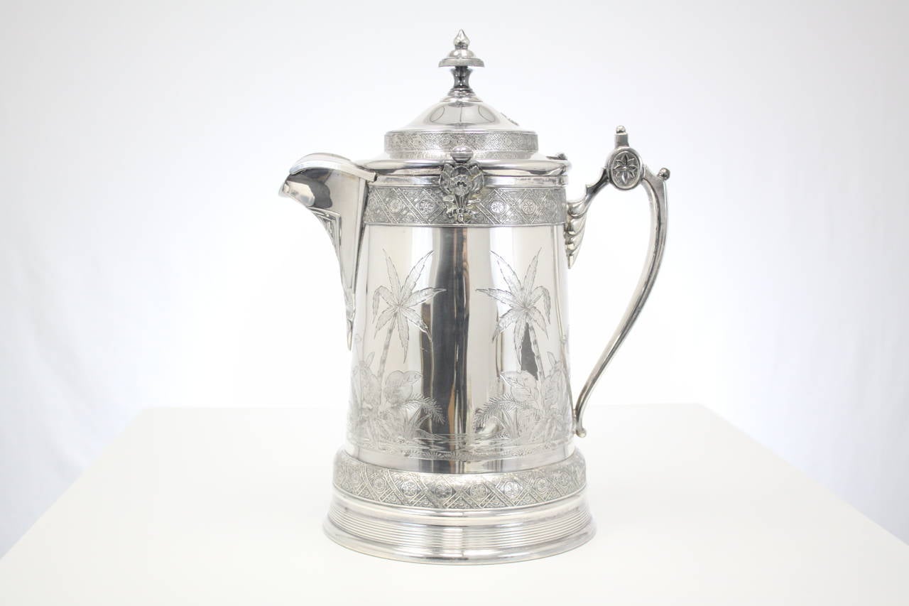 19th century silver plate ceramic lined Tankard from 1878. Crafted during the Aesthetics period, it is hand chased with a tropical paradise scene. Manufactured 5/10/1878.