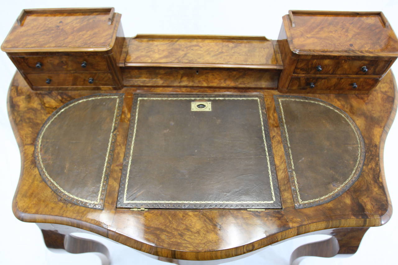 Constructed of Burled Walnut, this beautiful women's writing table also was used for reading. Center section can be raised for reading books at an angle. The table has one center drawer underneath and five additional drawers up top. Very warm burled