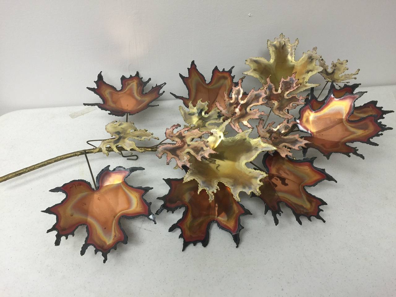 This detailed, multi-hued brass and copper wall sculpture is signed but not dated.  The array of fall colors is beautiful.  This piece is in very good condition. Measurements given are at widest points.