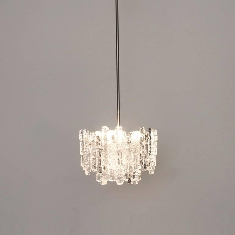 A very beautiful and elegant vintage chandelier, manufactured by Kalmar Austria in the 1960s. Lovely design, the chandelier has 6 sockets and two layers of extremely stylish textured solid ice glass sheets (18 pieces) dangling on it.
To be on the