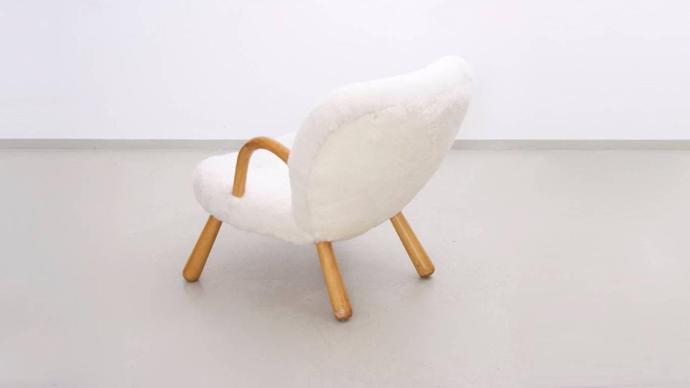Rare lounge chair named "The Clam Chair" designed by Danish architect Philip Arctander with arms and legs in beech and upholstered in sheep wool and leather buttons.
