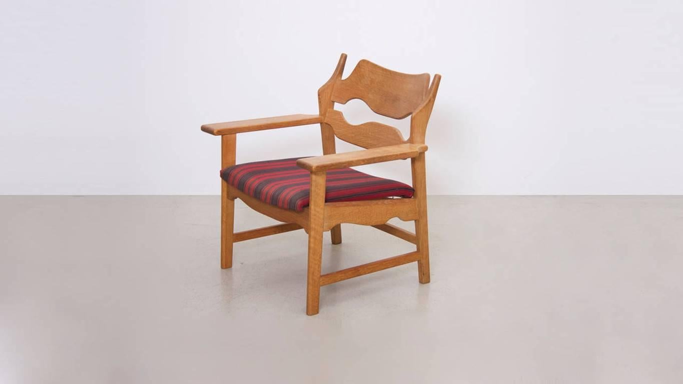 A 1960s oak lounge chair designed by Kjaernulf, featuring original fabric seats and a razor-shaped back rest. Excellent condition.
