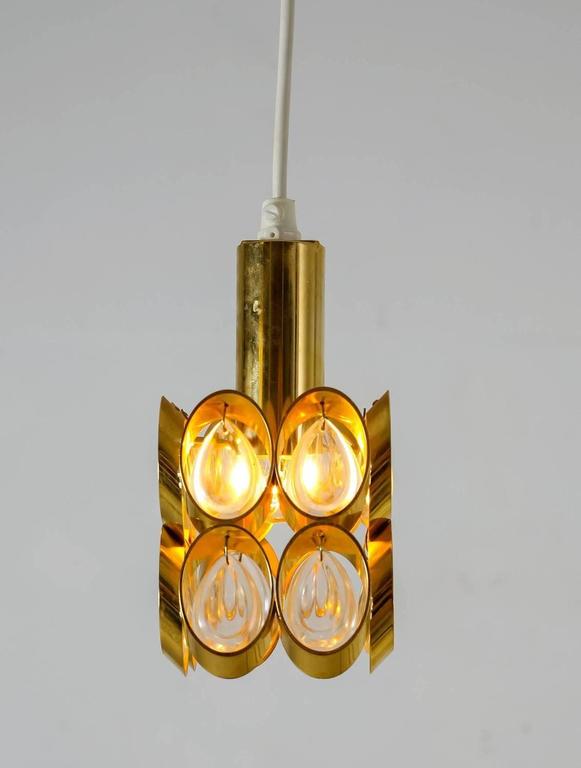 A pair of small and elegant Austrian brass pendants with crystal-like glass drops hanging in it. The glass gives a beautiful light effect.
To be on the the safe side, the lamp should be checked locally by a specialist concerning local requirements.
