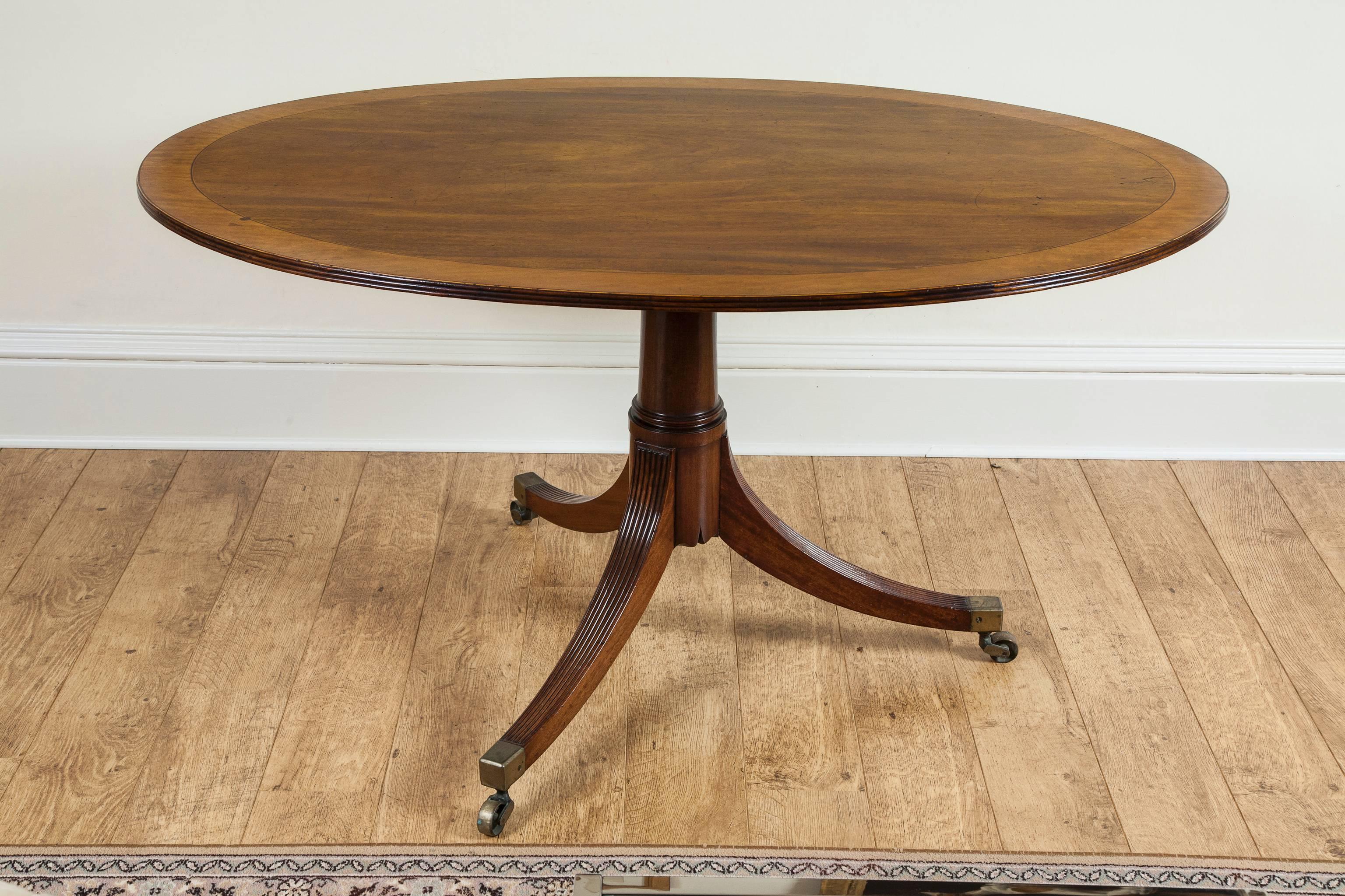 A handsome 18th century oval tilt top table with a triple reeded edge and satinwood cross banding, on a gun barrel stem and tripod base of reeded legs terminating in brass castors.
It is an exceptional table and the finest example. 
Of particular