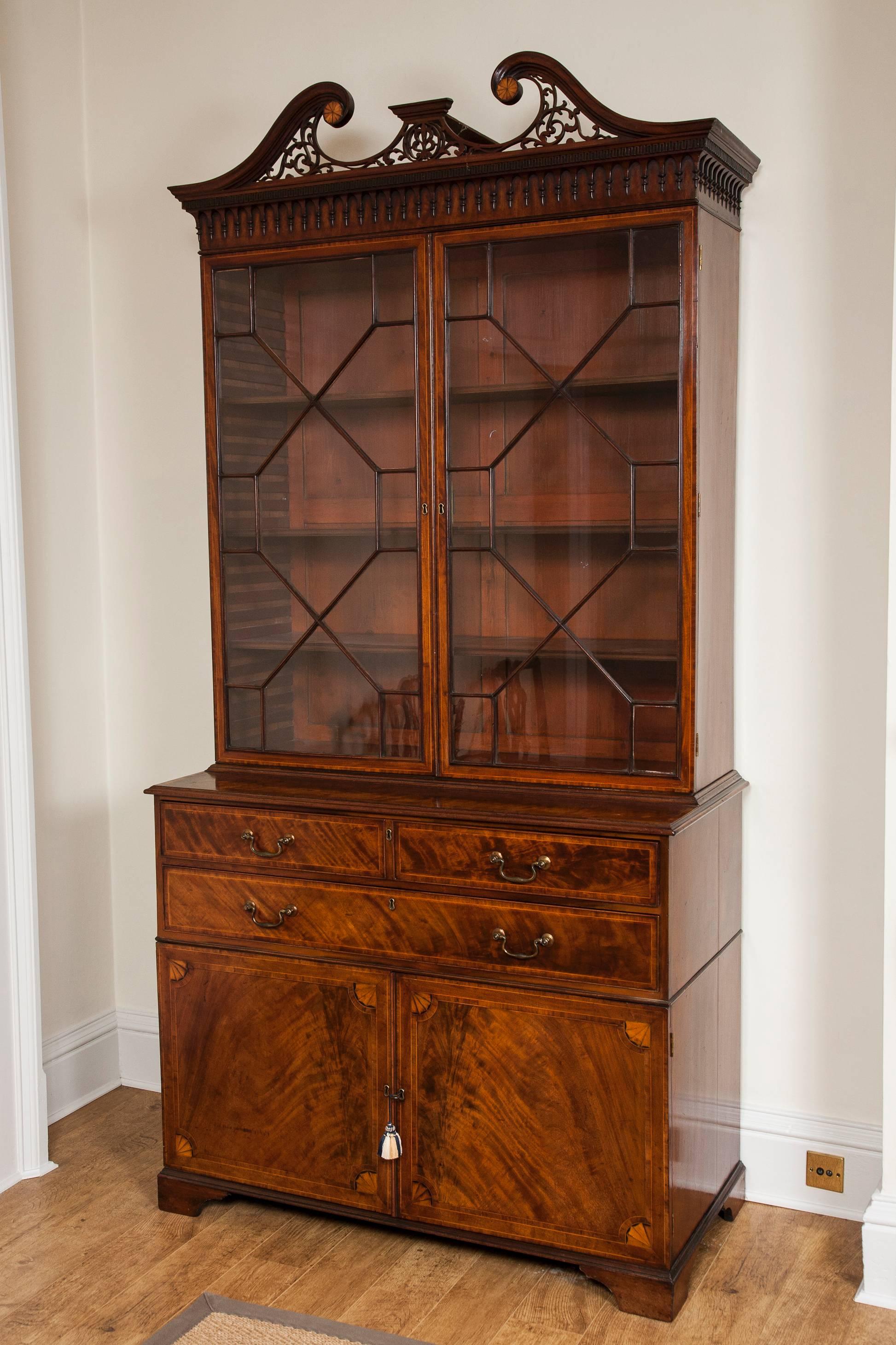 A superb late 18th century mahogany glazed door bookcase, the upper section with pierced mahogany swan neck pediment with inset satinwood patterae over dentil and arched and finial cornice, above two glazed doors and adjustable shelves. The lower