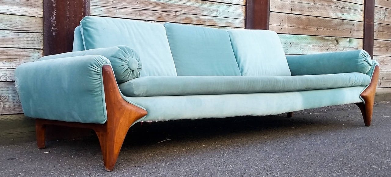 A stunning example of Mid-Century Modern design, this long gondola sofa was designed by Adrian Pearsall for Craft Associates. The sofa is currently upholstered in turquoise velvet that is very weathered and will require reupholstery.