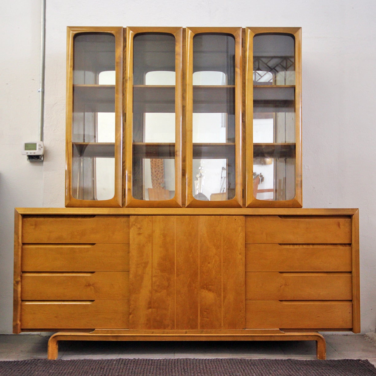 Flamed maple wall unit by Edmond Spence, made in Sweden. The wall unit is super clean and in excellent condition. 
This particular piece consists of two pieces, and the glass hutch top floats on the bottom. The bottom piece measures: 72