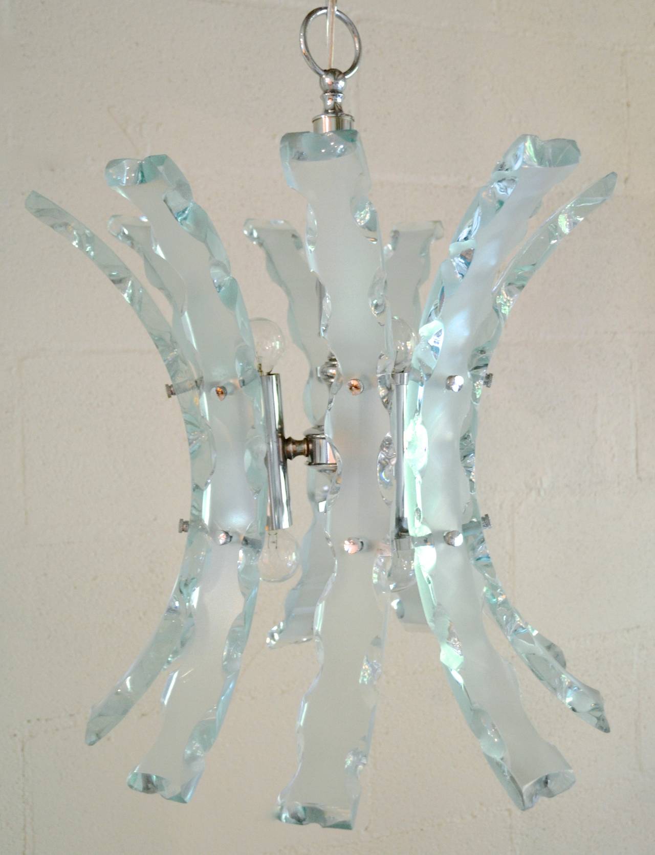 Italian Mid-Century Modern chrome and glass six-light chandelier, circa 1960. The glass is frosted on the surface but clear at the chiseled edges rendering great sparkle to a room. Attributed to Fontana Arte.

Main fixture is 21