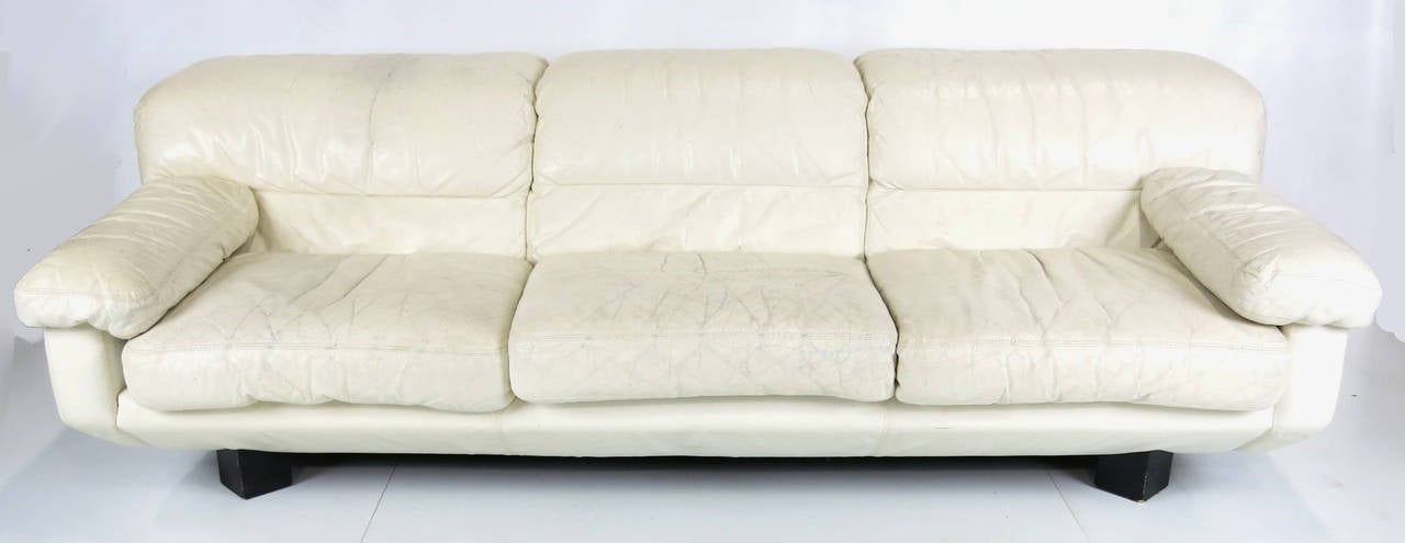 1980s Italian leather sofa raised on black enameled triangular feet in its original distressed white leather from the 