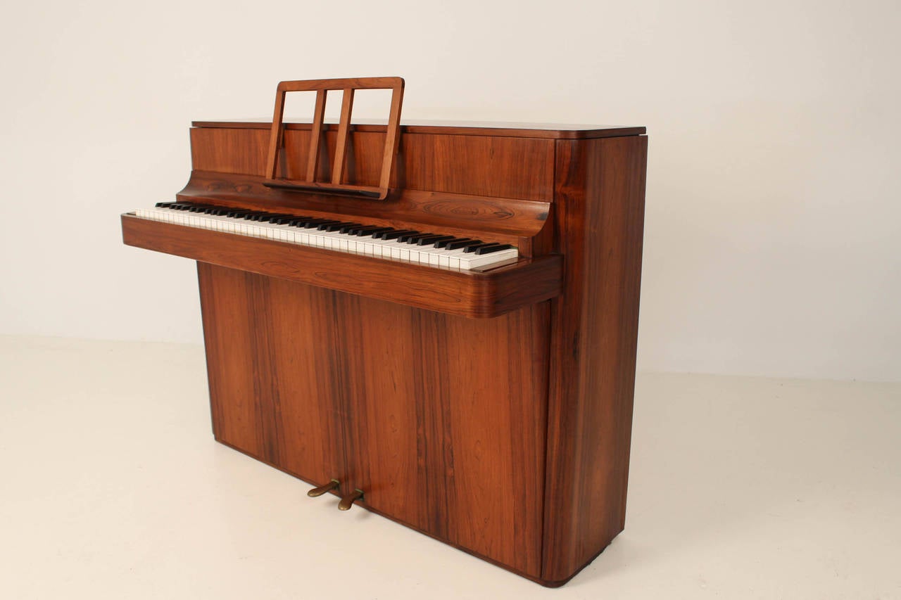 Stylish Mid-Century Modern rosewood piano by Brodrene Caspersen Denmark.
In good working order.
Rosewood has a beautiful patina.