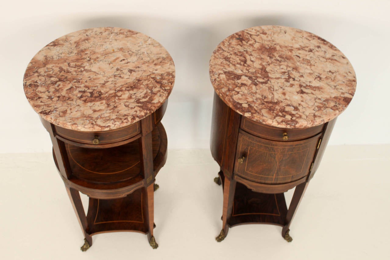 Stunning pair of rosewood and satinwood Louis XV style nightstands by De Coene Frères, Belgium.
With inlay and gilt bronze mounts.
The beautiful round marble tops are original and not broken or damaged.
De Coene Frères were famous for their