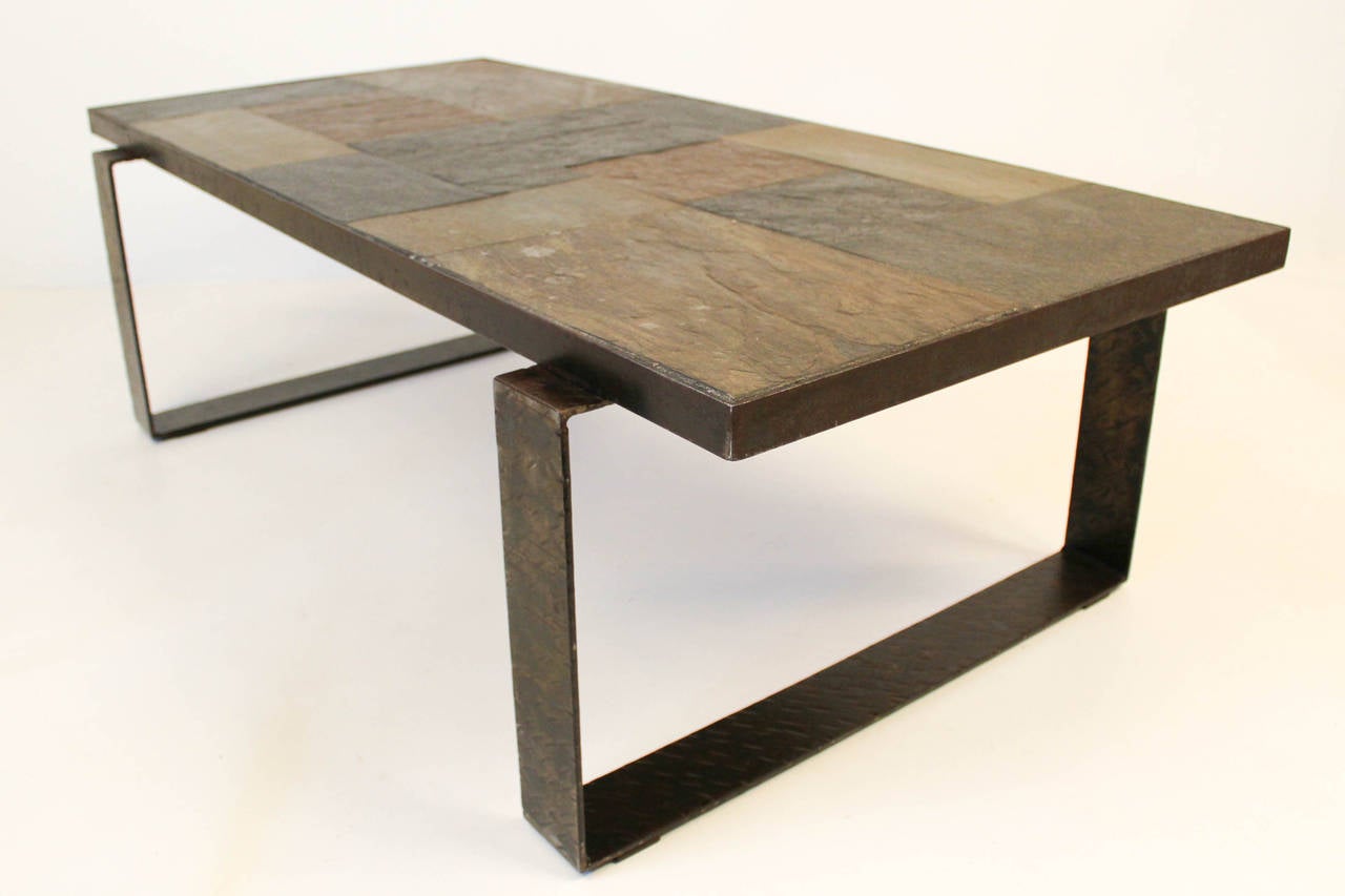 This vintage Brutalist coffee table attributed to dutch designer Paul Kingma is an early version of the 1960s with the top made of concrete,slate and glacial stones.The rectangular top sits on a solid iron hammered frame.