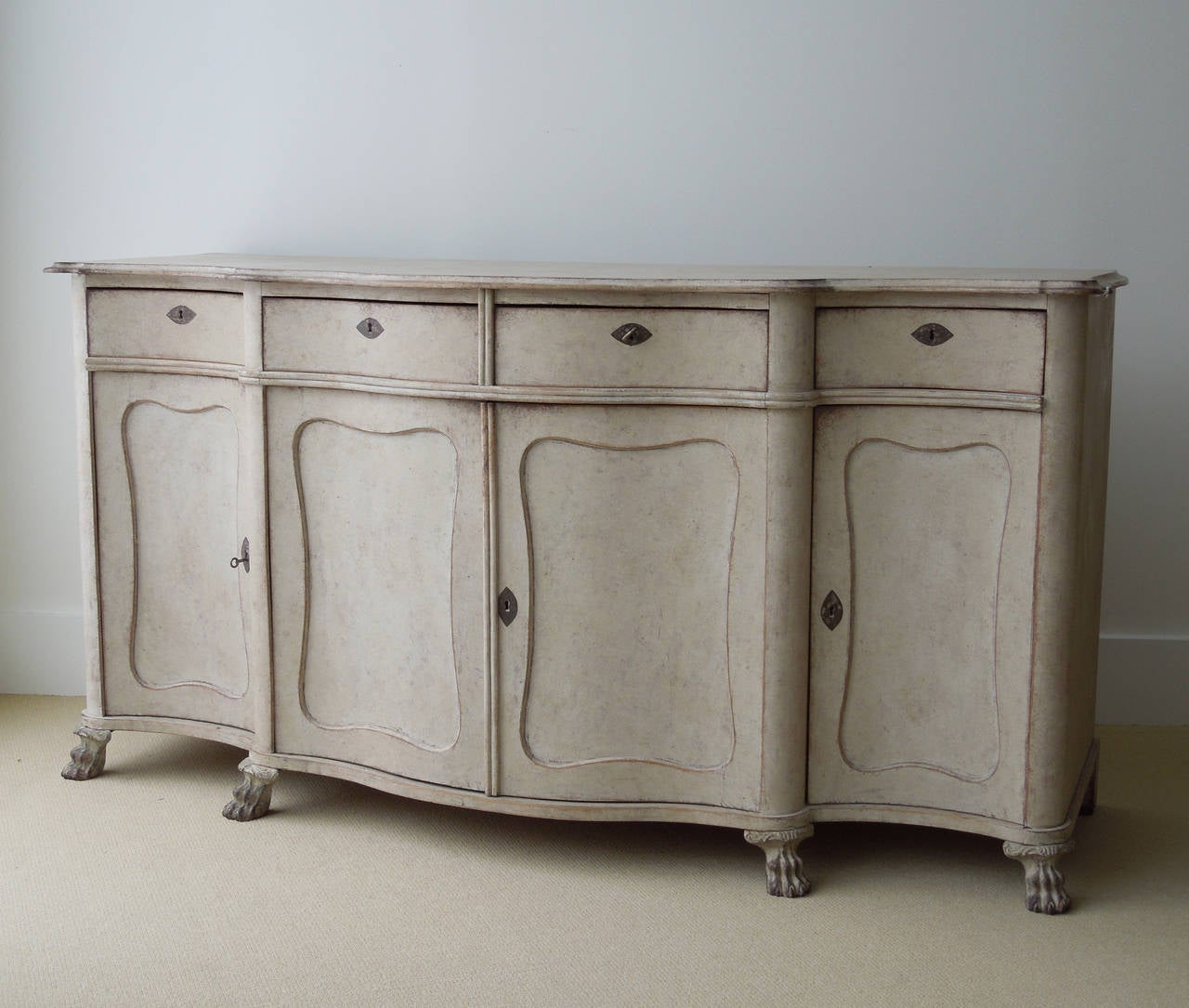 Swedish painted long sideboard cabinet with serpentine form, molded or beveled top edges, stepback sides, upper drawers, paneled lower doors and front paw feet.