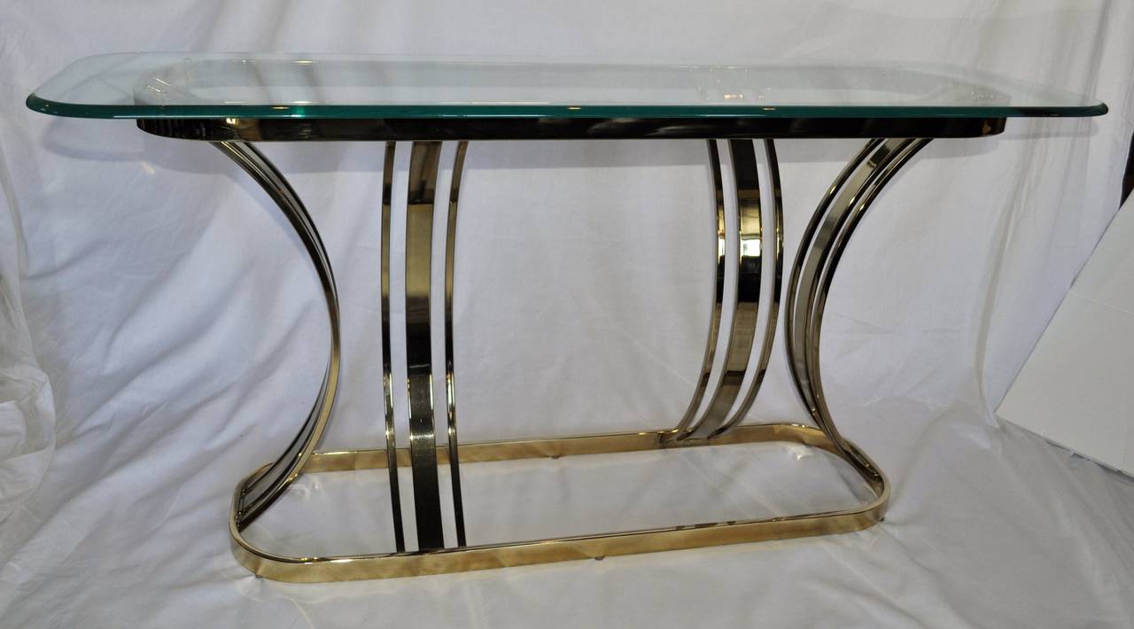 Sculptural brass console table with one inch thick beveled glass top in the style of Milo Baughman.