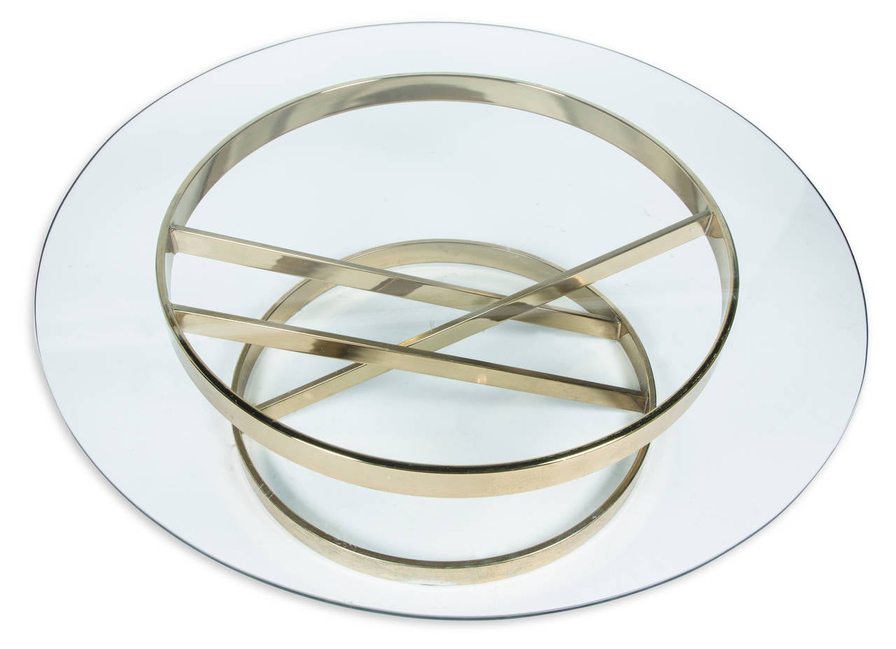Modern round cocktail table with angular brass base and 1/2 inch thick glass top.  Style of Milo Baughman.