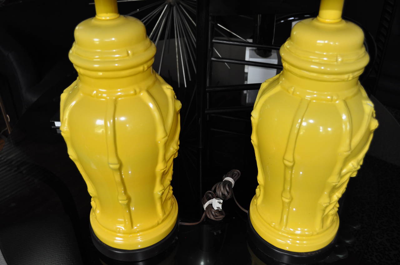Pair of sunny yellow glazed Hollywood Regency or Palm Regency chinoiserie faux bamboo table lamps. These Mid-Century Modern era lamps feature ceramic ginger jar shaped ceramic bodies with detailed raised bamboo latticework relief. Mounted on wood