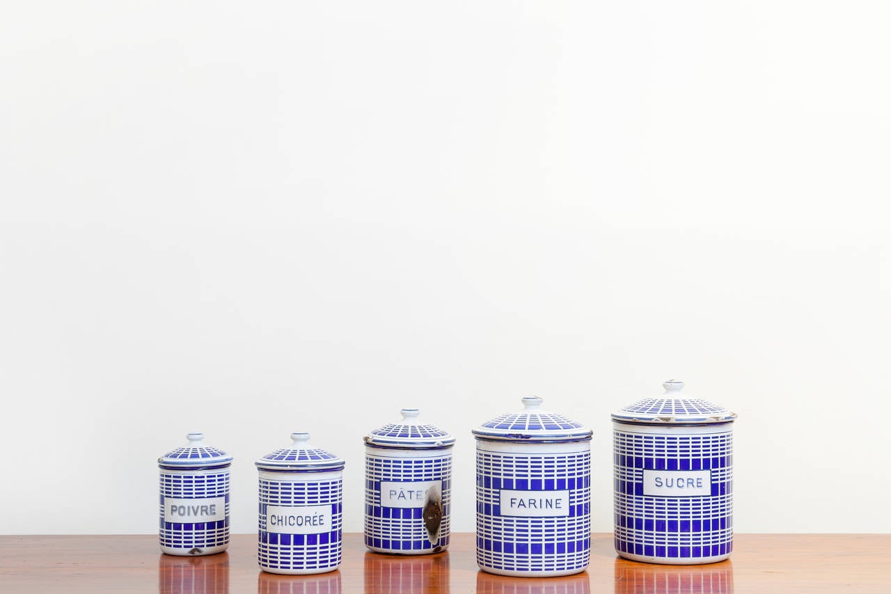 Set of five French enamel canisters, circa 1920. Graduated in size, largest 7.5 inches tall to smallest 5 inches tall. Cobalt blue and white plaid pattern.