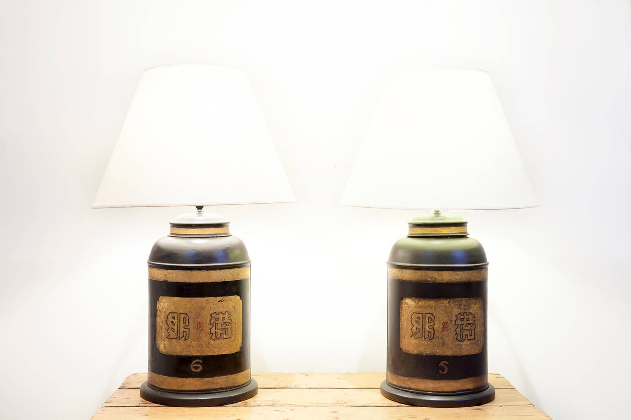 Pair of toleware tea caddy lamps, circa 1900, England. Black ground with gold painted Chinese characters and banding. Marked Parnell & Sons, Bristol.