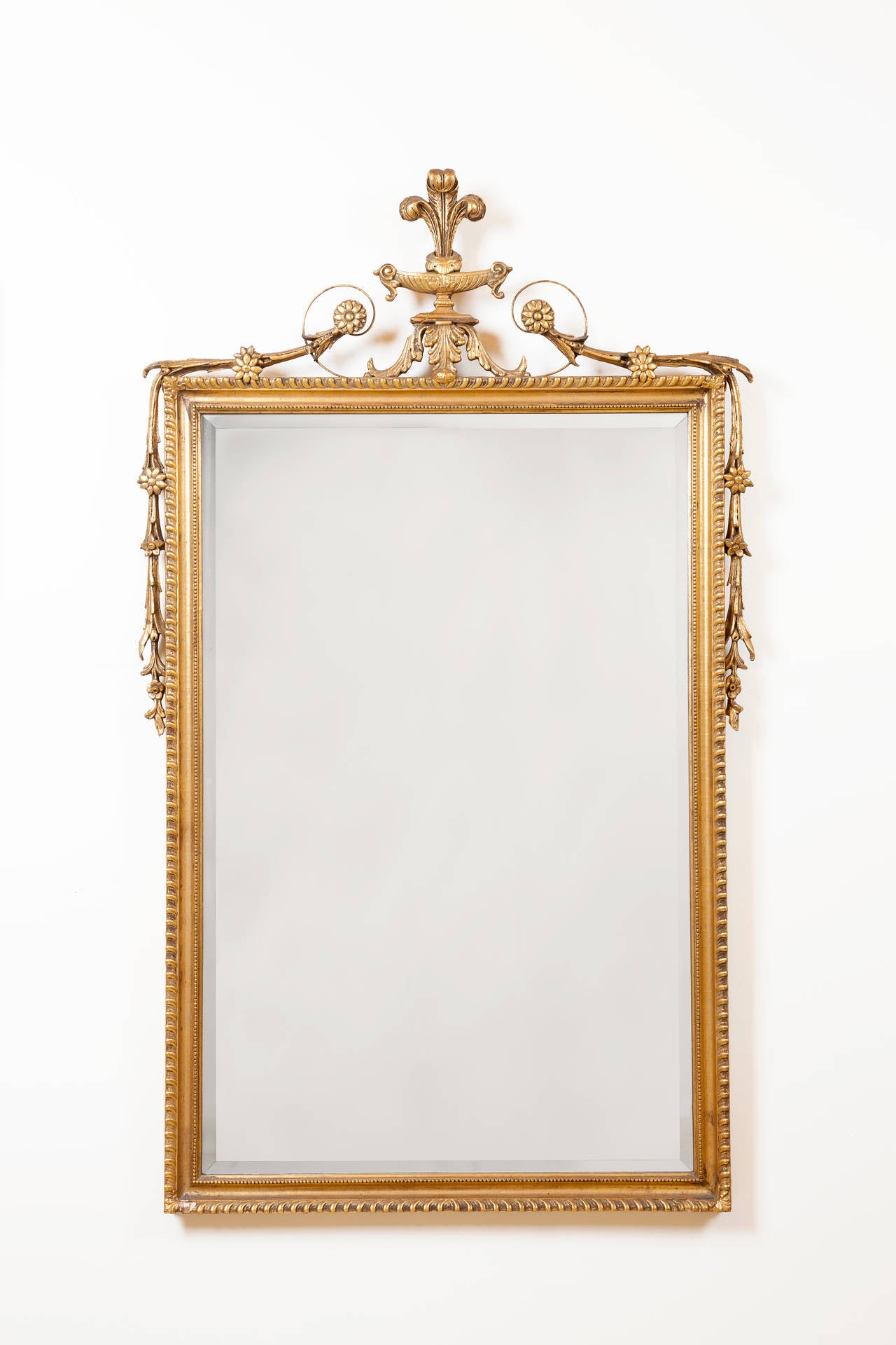 19th century English giltwood mirror with Prince of Wales feathers at top and carved rosettes and foliage bordering the frame. Adam style.