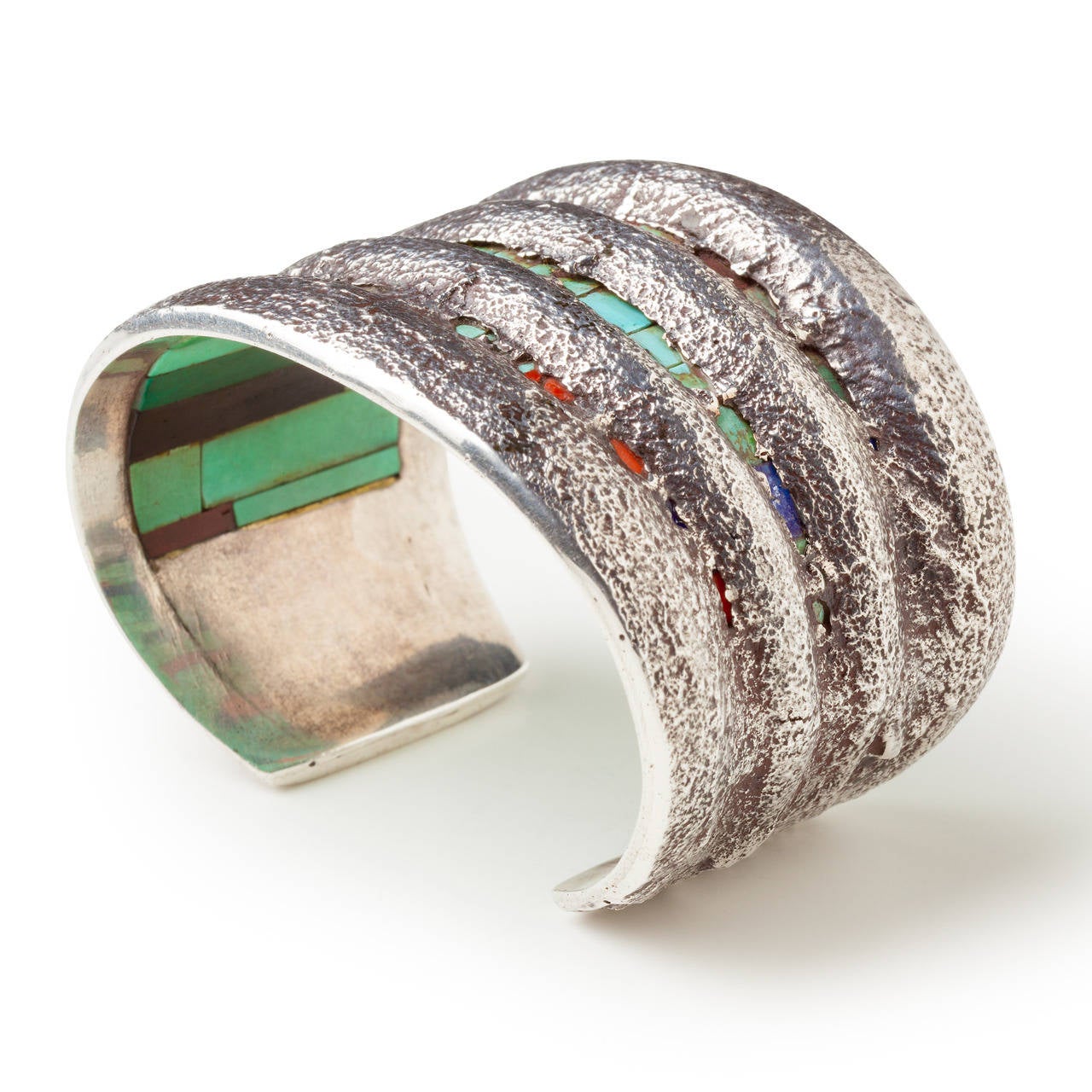 An astonishing example of the work of Charles Loloma, this bracelet demonstrates both his mastery of silversmithing as well as his unsurpassed lapidary work. Constructed of tufa cast silver, and inlaid with 51 pieces of hand-cut turquoise, lapis,