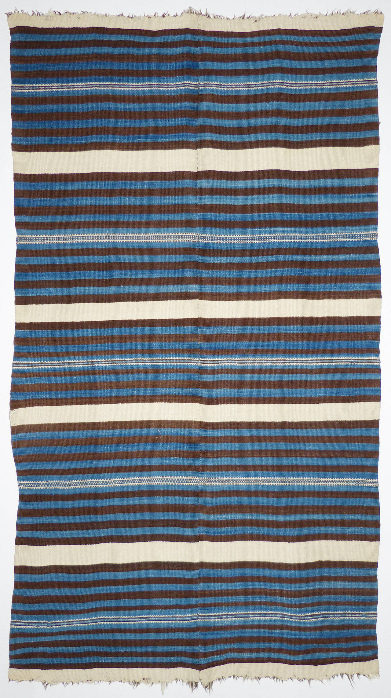 A beautiful banded Rio Grande blanket, c. 1870.  Featuring alternating stripes of natural white, natural brown, and light and dark dyed indigo. Made by Hispanic Americans in the villages along the Rio Grande in Northern New Mexico, it was woven on a