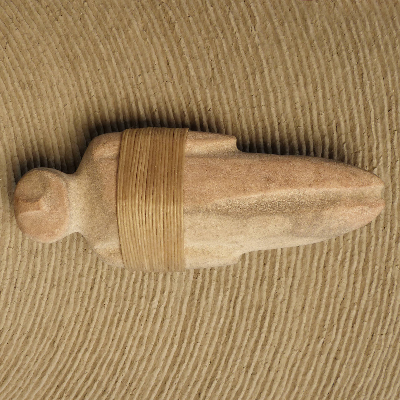 A traditionally made and fired large corrugated plainware olla with two large humanoid stone fetishes attached above the shoulder by contemporary Wyandot artist Richard Zane Smith.  Smith is known for his use of prehistoric techniques like the