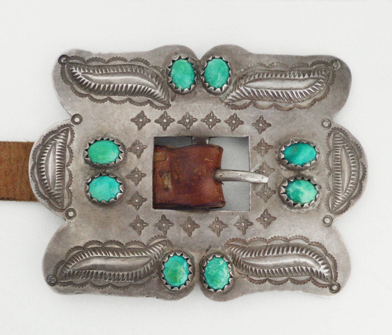 An exquisite Third Phase Concho Belt, c. 1920. This belt consists of six conchos and a buckle, made of heavy gauge silver with repousse, stamped and chiseled elements. It is set with thirty-eight hand made bezels, with highly unusual Persian-cut