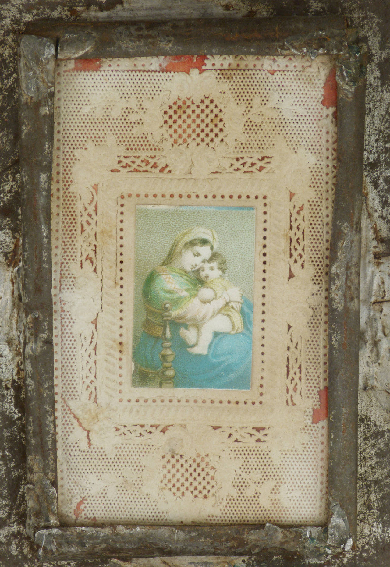 A charming New Mexican stamped tin frame, with a paper collage of Madonna and child. Scalloped edges, and polychrome paint add character to this piece. Although Hispanic made,  collected at Laguna Pueblo in New Mexico. 8.5