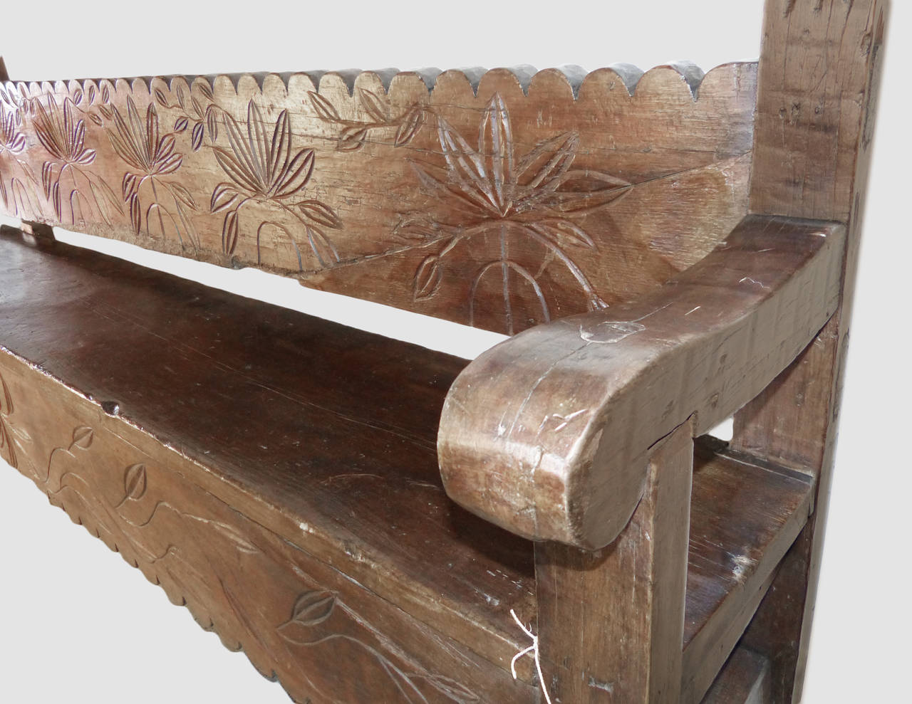 This wonderful large bench is made of hardwood and features scalloped edges along the back and front apron, as well as sinuous floral carving. Heavy curved armrests complete the piece. Perfect for a long hallway or under a portal for the perfect