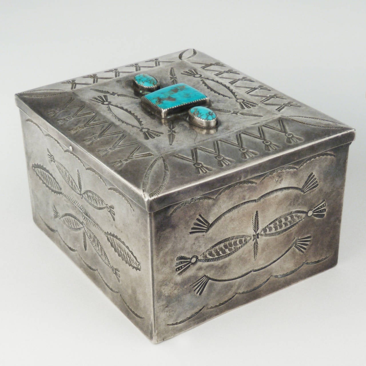 A beautiful handmade Navajo sterling silver box from the 1940's, with intricate stamp work on five sides, hinged and set with three turquoise cabochons. The largest piece of turquoise is identifiable as being from the Morenci mine in Arizona. 3 1/2