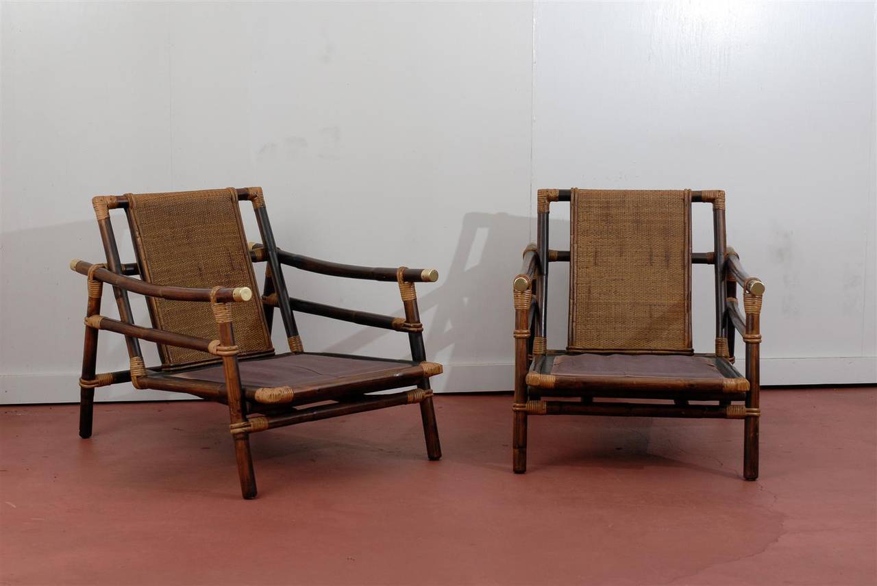An Exceptional pair of Campaign style lounge chairs.  Bamboo frame with a beautiful raffia seat back and solid brass accents on the arms.  Aged to Absolute Perfection !  These unusual chairs were designed by long time Ficks Reed designer John Wisner