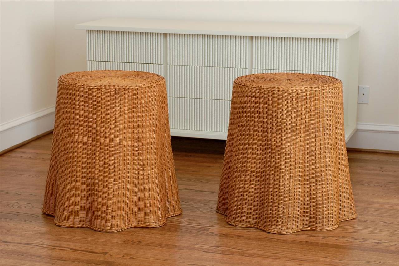 A fabulous pair of vintage wicker end tables, circa 1960. A beautifully conceived and executed design, the wicker is woven to create a table drape effect. Hardwood insert beneath the top adds strength and stability. These dramatic pieces are a
