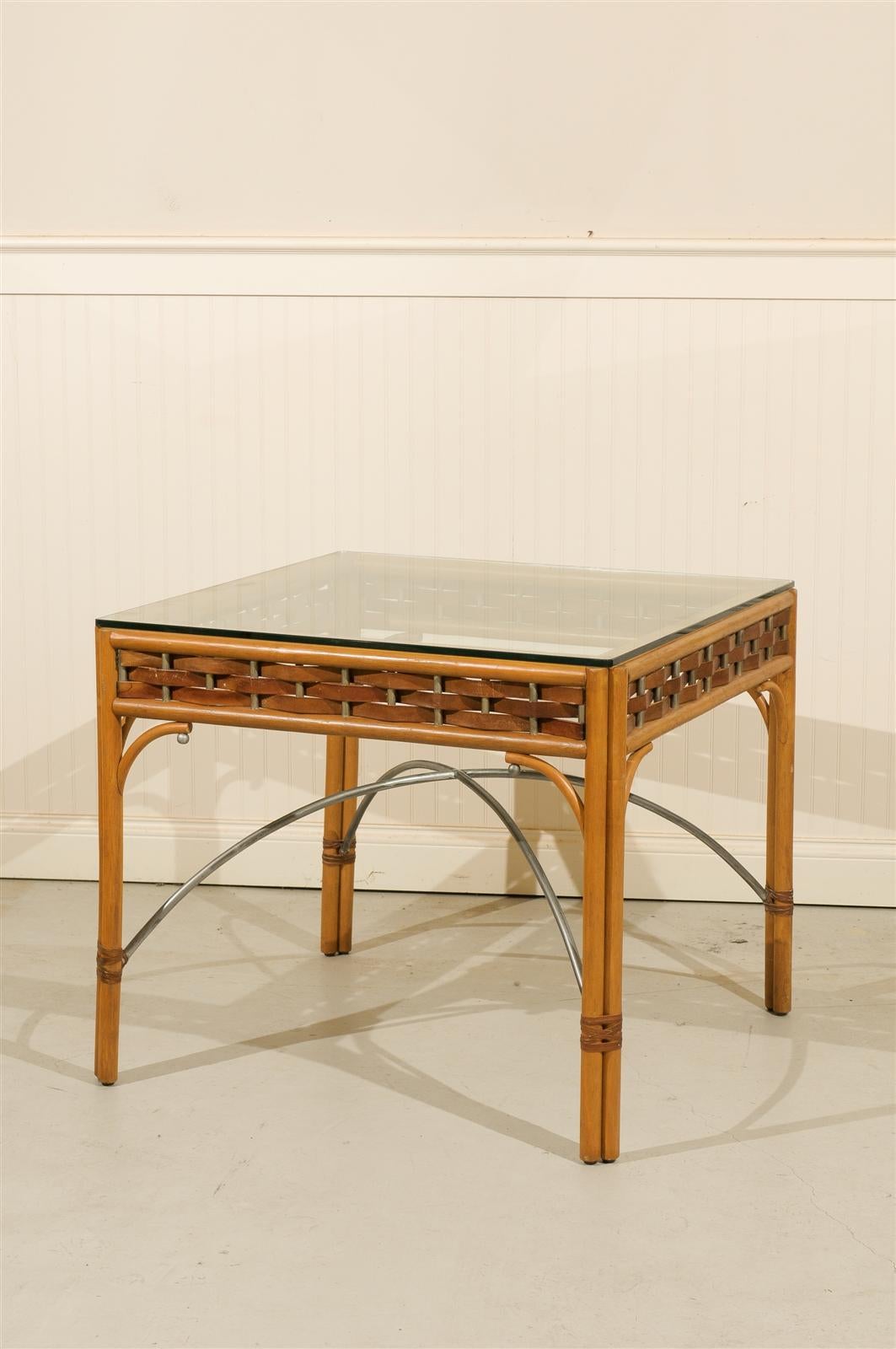 A beautiful vintage rattan and glass card or game table, circa 1980.  Lovely leather and wrought iron accents highlight the piece.  Excellent Restored Condition, the table has been re-lacquered.  Matching set of four ( 4 ) chairs are available in a