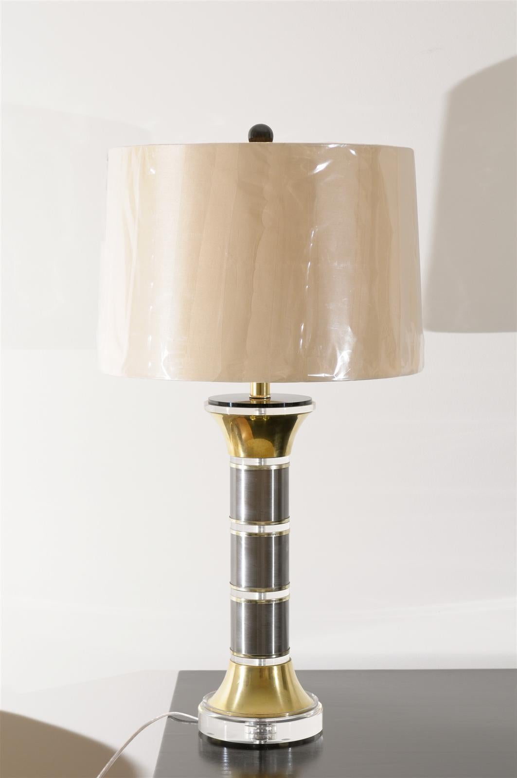A sophisticated pair of vintage column lamps, circa 1970. Alternating sections of Lucite and stainless steel with solid brass accents. Dramatic pieces with wonderful scale. Fabulous jewelry! Excellent restored condition. The lamps have been re-wired