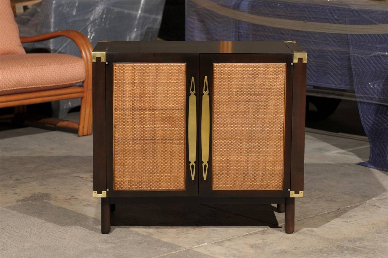 A stunning pair of vintage multipurpose cabinets by Heritage, circa 1960. Beautiful walnut case construction with rattan raffia door panels and solid brass hardware and case accents. Exceptional quality. May serve as end tables or nightstands.