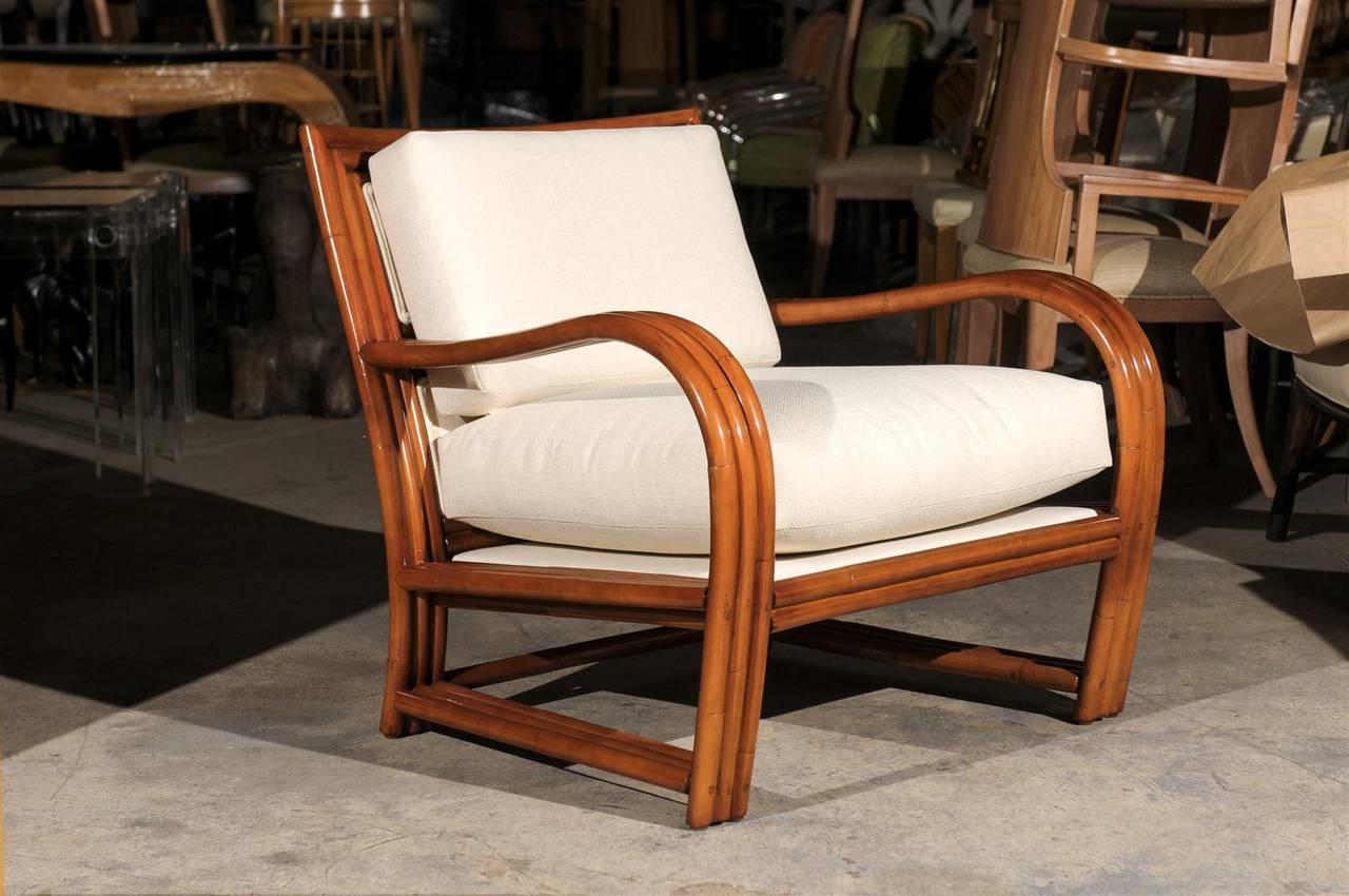 A stellar pair of large-scale rattan club chairs, circa 1970s. Stout, expertly made pieces highlighted by a fabulous upholstered two panel back detail. Extremely comfortable. Excellent restored condition. The chairs have been re-lacquered and