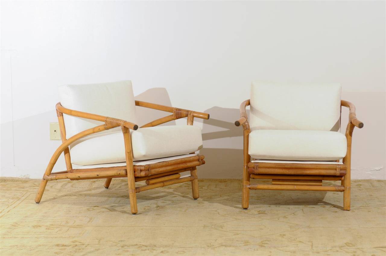 A striking pair of modern rattan lounge chairs by Ficks Reed, circa 1960s. A beautifully conceived and executed design. Handsome brass escutcheons mark the chair arms. Fine, expertly made pieces which offer great comfort. Excellent restored