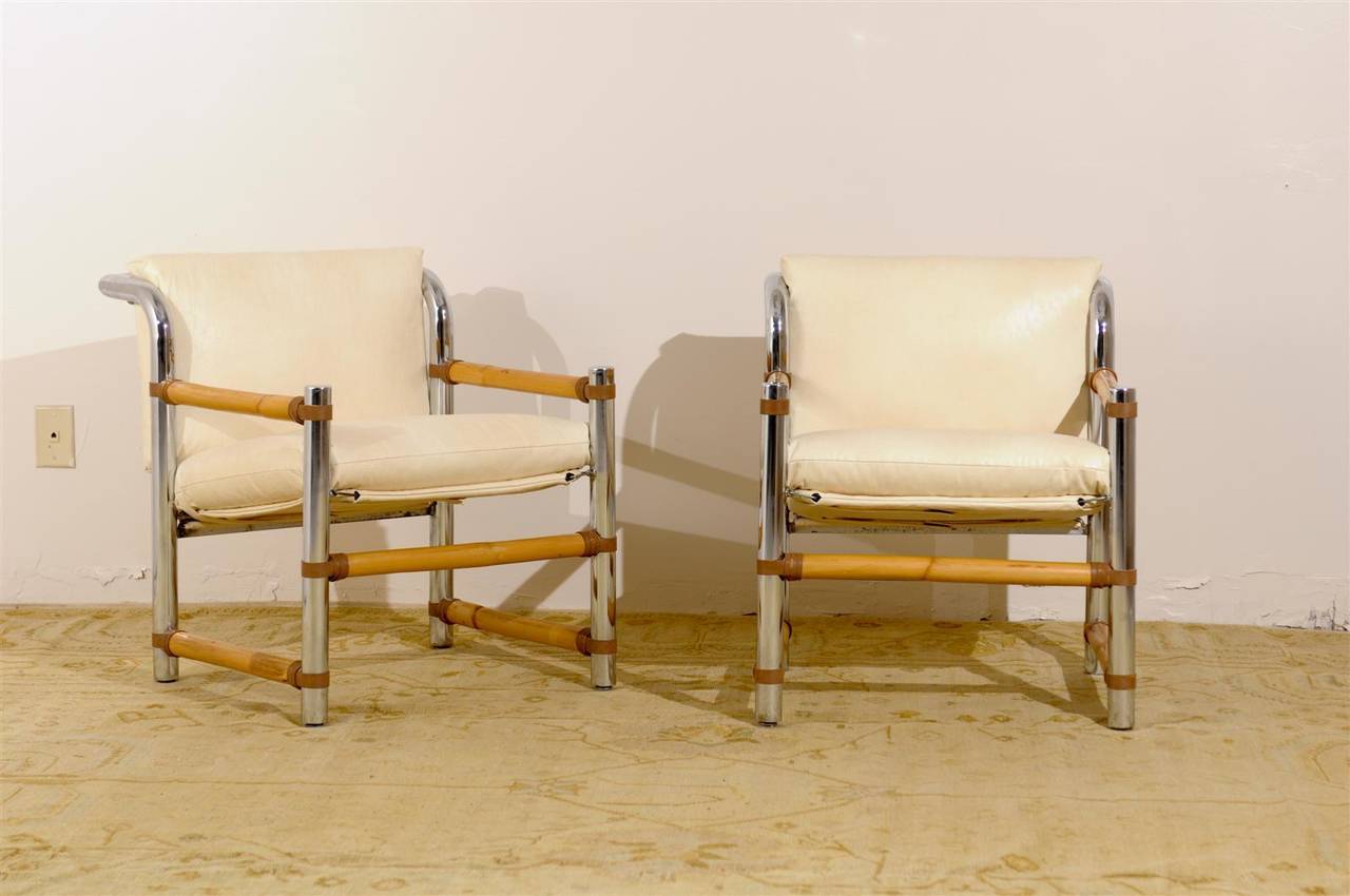 An unusually beautiful pair of vintage lounge chairs, circa 1970. Stout chrome construction with bamboo and leather accents. Exceptionally made pieces. Newly upholstered in a fine Kravet faux parchment fabric. Excellent restored condition. The