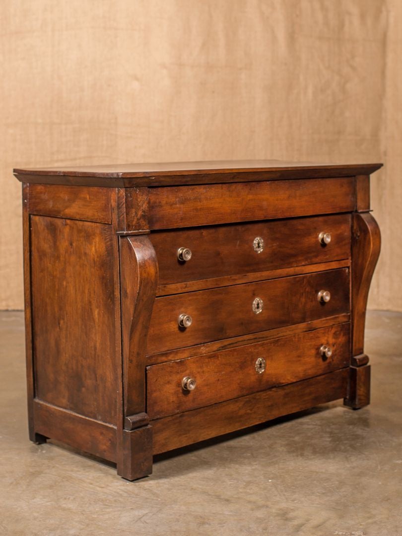 19th century French Restauration period commode. Solid walnut. This handsome commode has a hidden apron drawer above three drawers with bronze escutcheons and drawer pulls flanked by scrolling pilasters. Raised on bracket feet, Lyon, France.