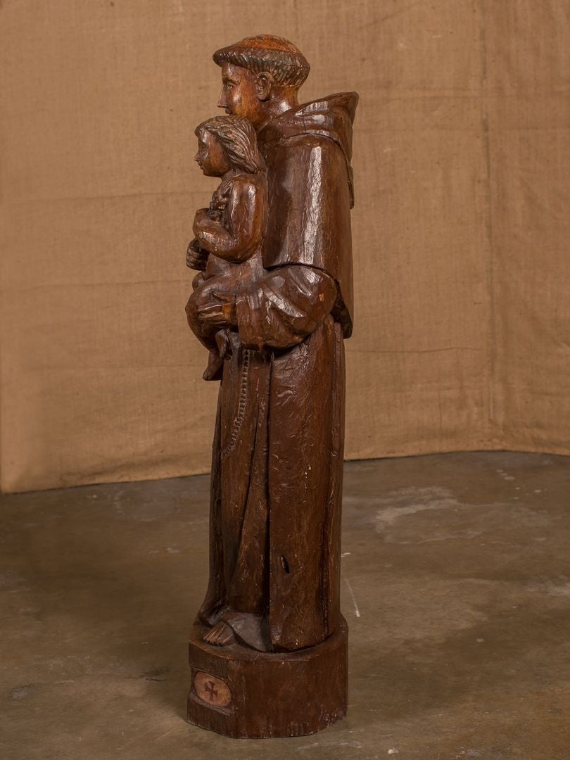 Wonderful French religious statue of St. Antoine de Padoue. The statue, hand carved from walnut wood, depicts St. Anthony holding the Christ Child in his left arm and a book of psalms in his right hand with the words 