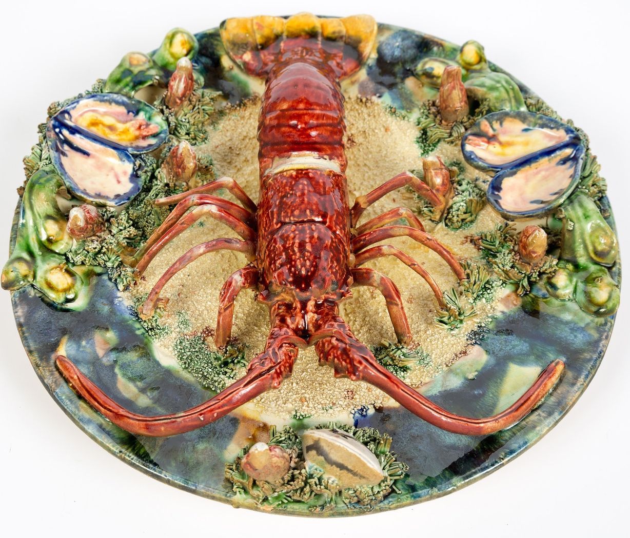 Very collectible Palissy style majolica langouste (spiny or rock lobster) plate. Portuguese trompe-l'oeil platter features a bright red langouste on a textured and mottled ground of sand, mussels, seaweed and shells. Impressed marks on the reverse.