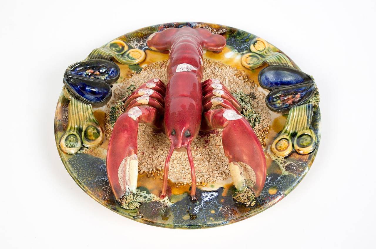 Palissy style majolica homard lobster plate. Portuguese trompe-l'oeil platter features a bright red lobster on a textured and mottled ground of sand, mussels, kelp and shells. Highly collectible.

We have a set of four plates: langouste, crab,