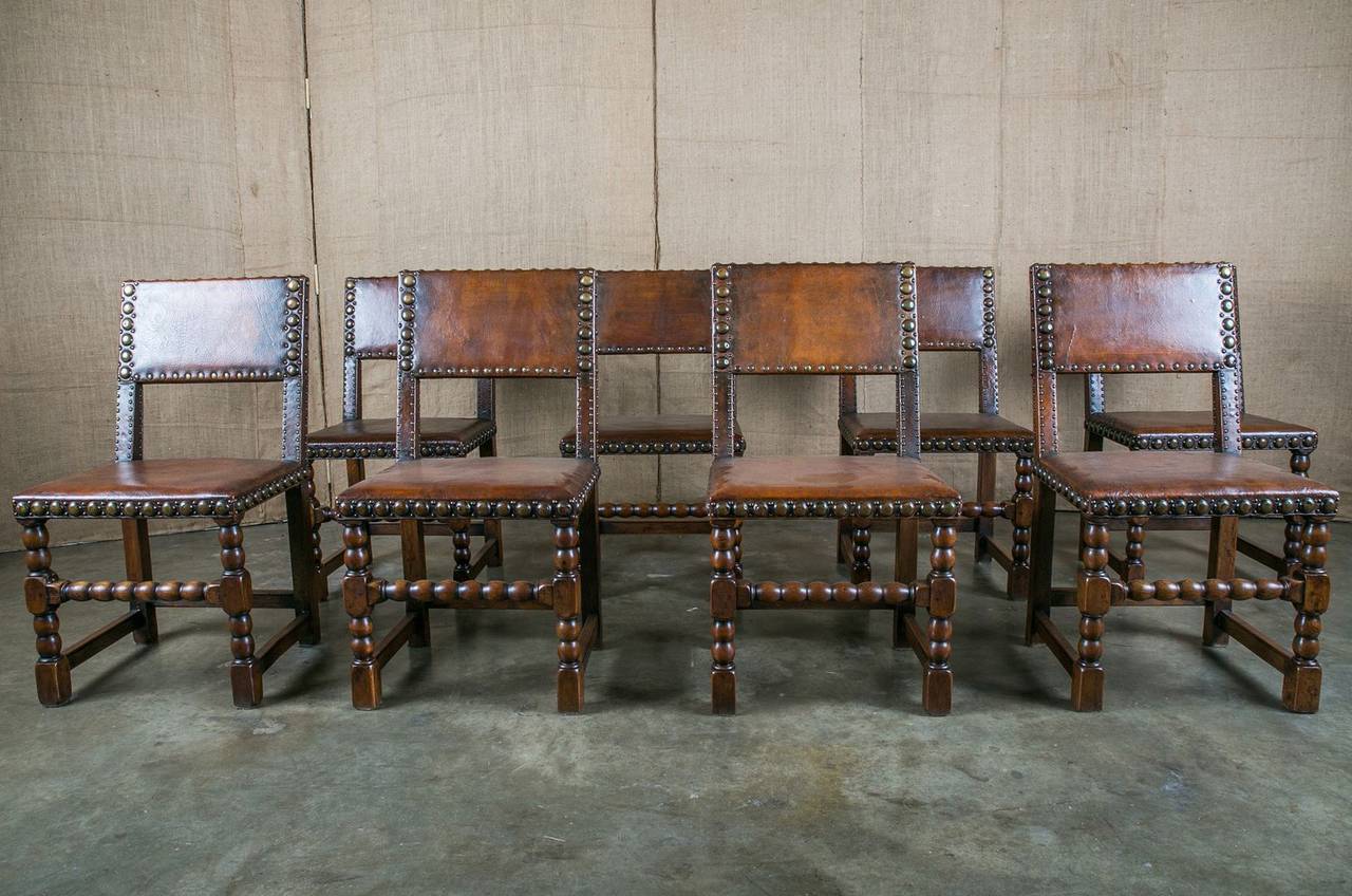 Handsome set of eight French Renaissance Revival walnut dining chairs by Maison Gouffé, Paris. Original leather backs and seats with large nailhead trim. Supported by two front bobbin legs joined by a turned stretcher and two straight back legs
